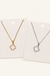 Clover necklace in gold and silver on warm cream background
