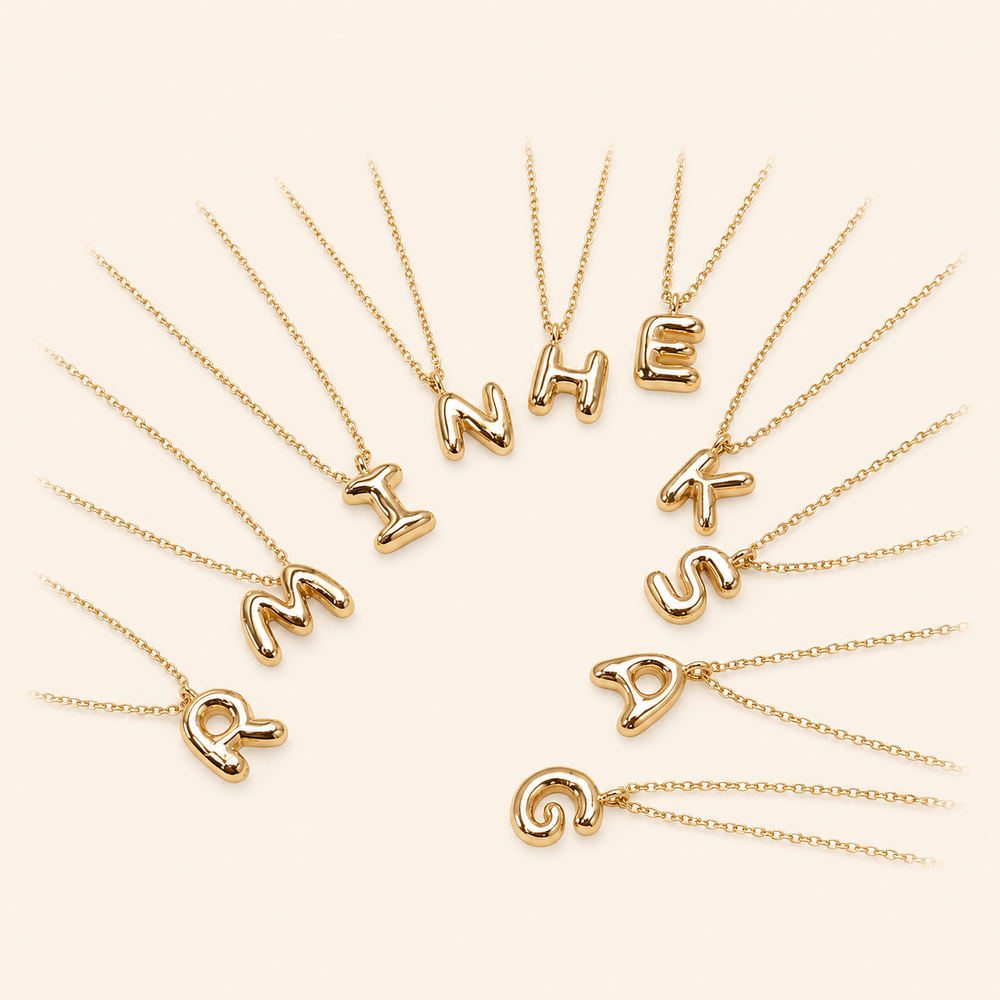 Bubble initial necklaces on warm cream background