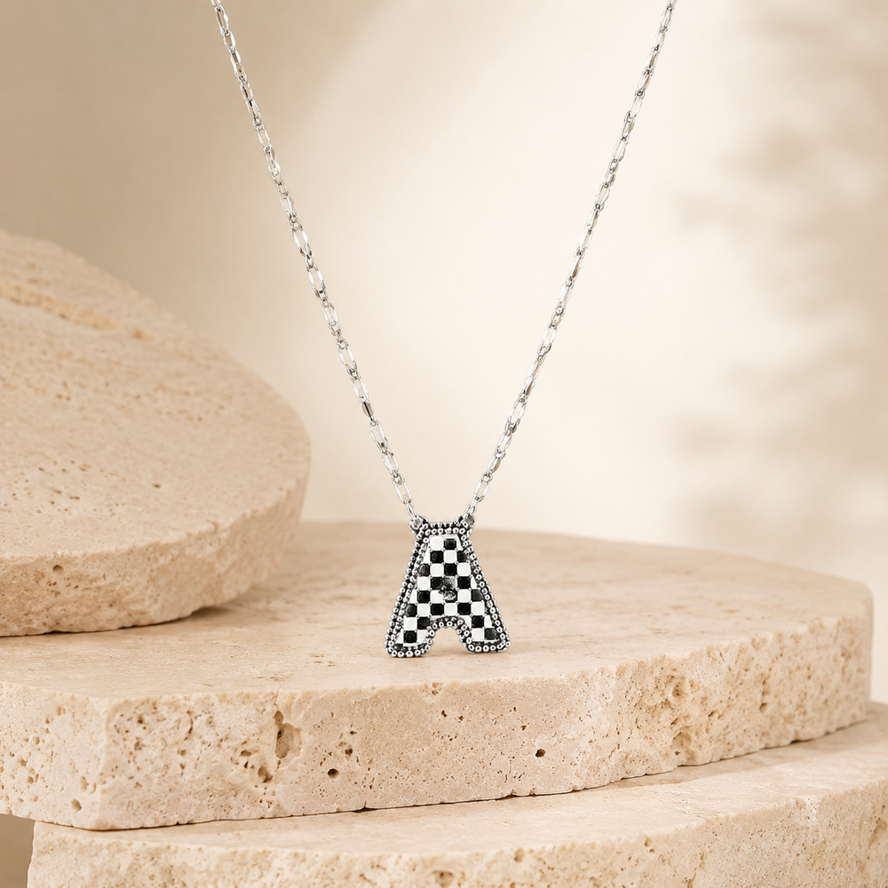 Checkered Bubble Initial Necklace on cream stone display