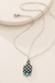 Western Checkered Cattle Tag Pendant Necklace on a warm cream stone display