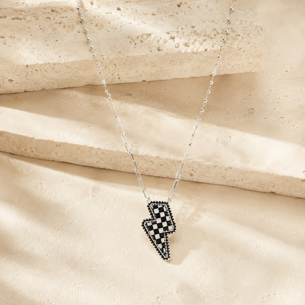 Checkered Lightning Bolt Necklace on cream stone background