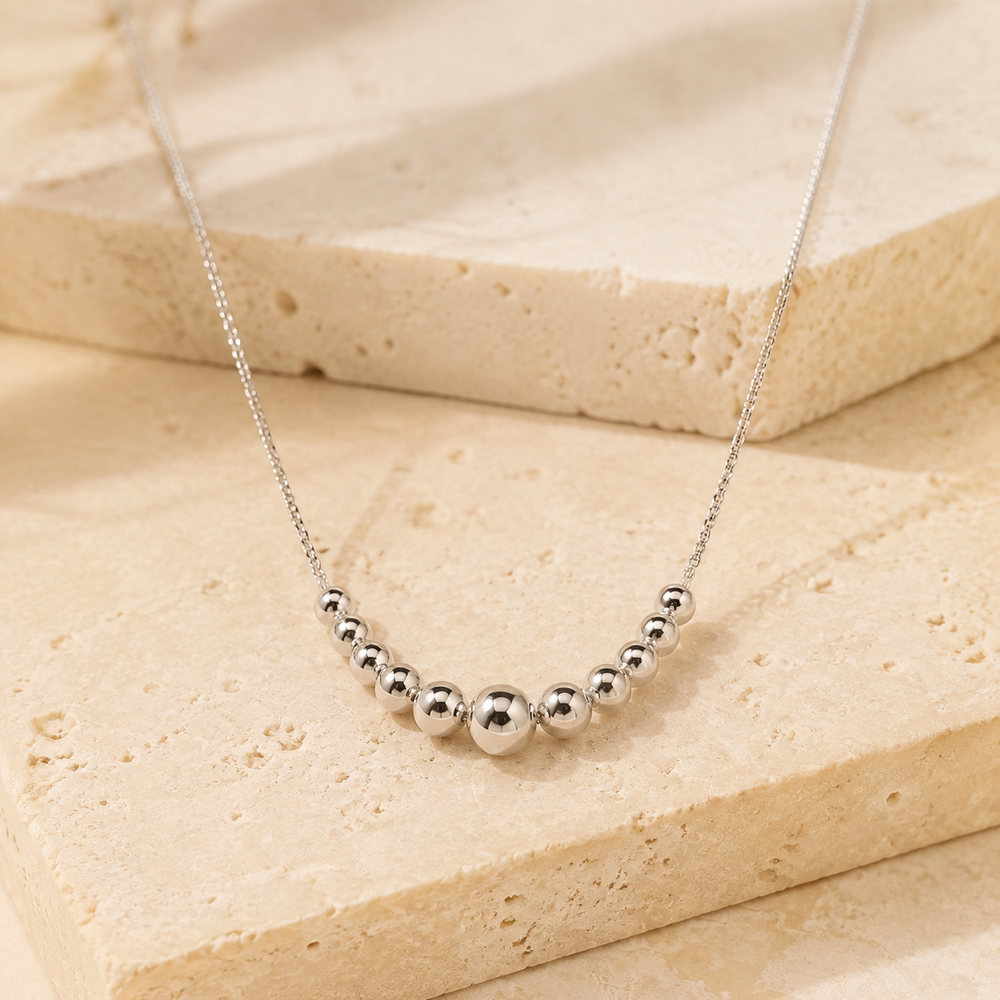 Sterling Silver Tier Bead Necklace on cream stone background